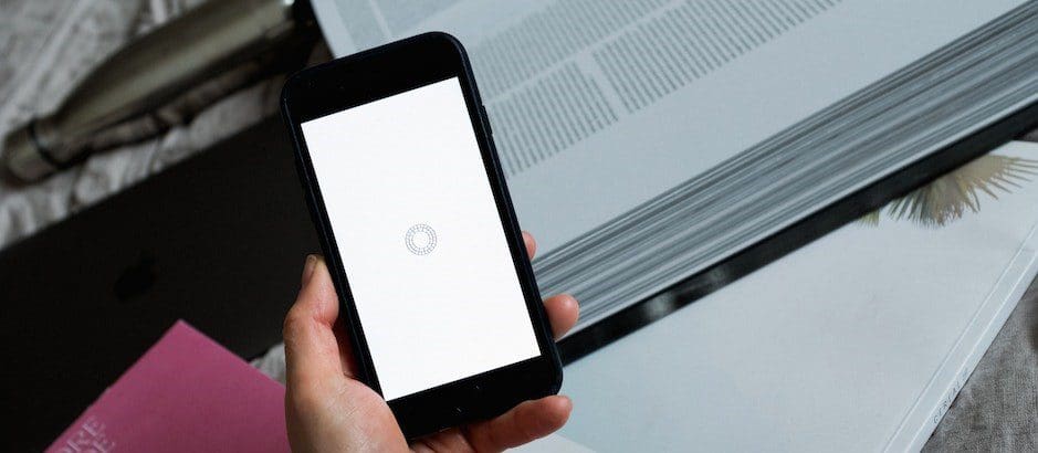 Човек държи телефон в ръка, на екрана на който се показва икона за зареждане на страница